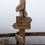 A wooden signpost pointing to major cities in a misty mountain setting. Perfect for travel themes.