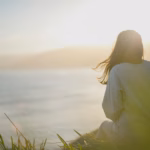 woman wearing gray long-sleeved shirt facing the sea